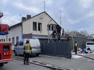 Akcja ratownicza na miejscu pożaru. Na zdjęciu widać jak policjantka znosi po drabinie psa.