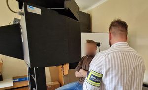 Zatrzymany mężczyzna podczas wykonywanych z nim czynności. obok niego znajduje się nieumundurowany policjant.