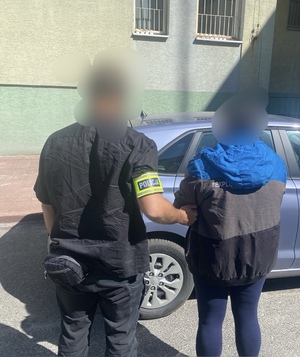 nieumundurowany policjant trzyma zatrzymaną kobietę