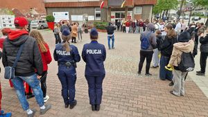 Dwie policjantki oraz grupa uczestników gry, zebrani przed Urzędem Miasta Pabianic.
