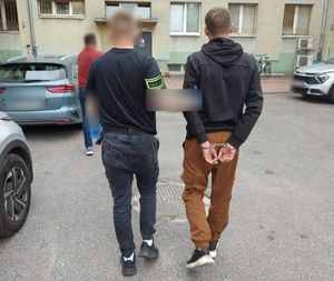 Kryminalny doprowadzający do komendy zatrzymanego mężczyznę.