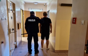 Policjant stoi z zatrzymanym mężczyzną.