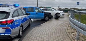 Miejsce zdarzenia drogowego, na którym widać policyjny radiowóz i rozbite pojazdy.