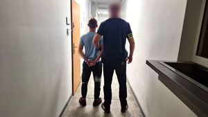 Kryminalny stoi z zatrzymanym mężczyzną.