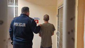 Umundurowany policjant stoi z zatrzymanym mężczyzną.