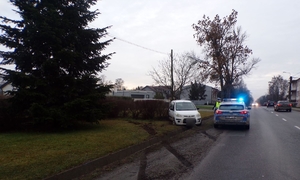 Biały pojazd w betonowym rowie, obok niego policyjny radiowóz.