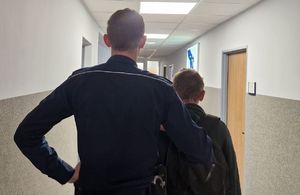 Policjant stoi z zatrzymanym mężczyzną.