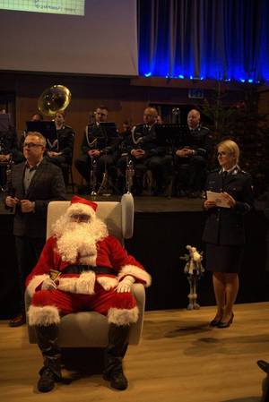 W fotelu siedzi Święty Mikołaj, obok stoi policjantka i Zastępca Dyrektora Placówki Opiekuńczo Wychowawczej w Porszewicach.