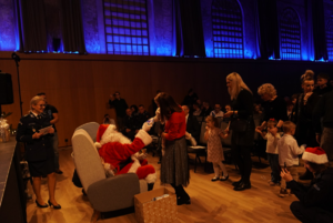 Kolejka dzieci i dorosłych podchodzących do Świętego Mikołaja.