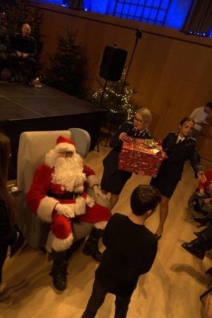 Policjantki podają prezenty Świętemu Mikołajowi, który wręcza podarunek chłopcu.