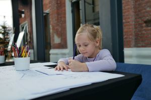 Dziewczynka maluje kolorowankę przy stoliku.