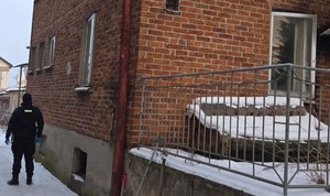 Policjant stoi obok ceglastego budynku.