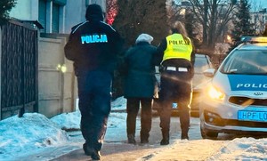 Policjanci prowadzą do radiowozu odnalezioną seniorkę.