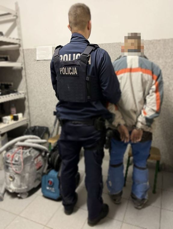 Policjant stoi z zatrzymanym mężczyzną.