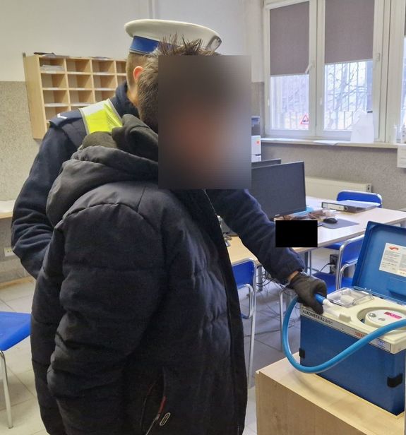 Policjant wykonuje wobec zatrzymanego badanie stanu trzeźwości.