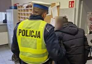 Policjant stoi z zatrzymanym mężczyzną.