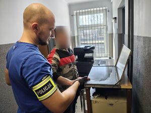 Policjant pobiera odciski palców podejrzanemu.