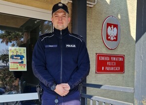 Dzielnicowy stoi przy wejściu do komendy.