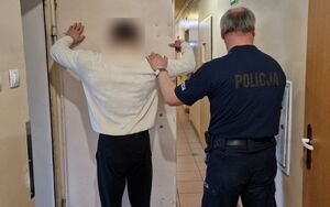 Policjant stoi z zatrzymanym mężczyzną