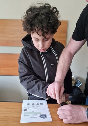 Chłopiec odbija odciski palców na karce papieru.