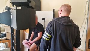 Nieumundurowany Policjant stoi obok podejrzanego mężczyzny.