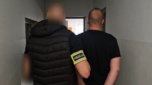 Nieumundurowany Policjant stoi obok podejrzanego mężczyzny.