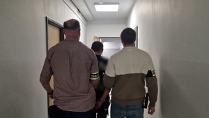 Dwóch nieumundurowanych policjantów i zatrzymany mężczyzna.