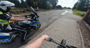 Fragment policyjnego motocykla obok niego stoi zatrzymany do kontroli jednoślad.