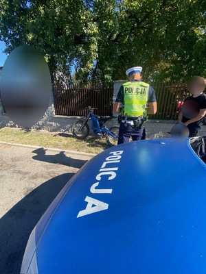 umundurowany policjant stoi przy jednośladzie obok niego stoi kierujący