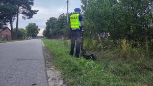 umundurowany policjant w kamizelce odblaskowej wykonuje oględziny hulajnogi elektrycznej