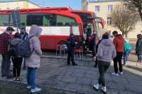 mieszkańcy oraz policjant stoją w kolejce przez autobusem służącym do oddania krwi.