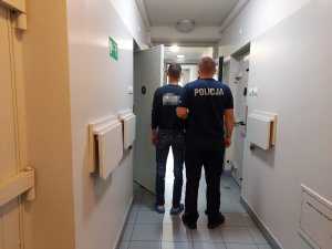 Policjant prowadzi zatrzymanego do celi.