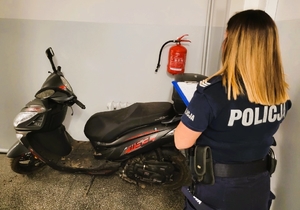 Policjanta wykonuje oględziny odzyskanego skutera.