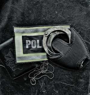 kajdanki policyjne leżące na opasce z napisem policja