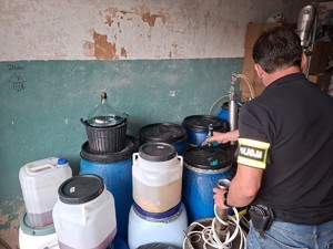 Policjant zabezpiecza przedmioty o produkty służące do nielegalnego wytwarzania alkoholu