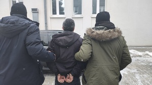 Policjanci prowadzą zatrzymanego mężczyznę