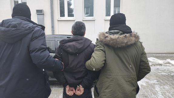 Policjanci prowadzą zatrzymanego mężczyznę