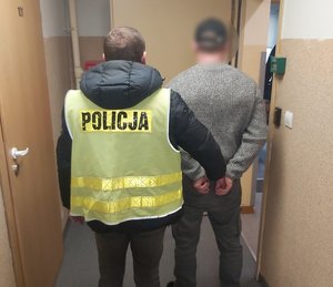 Policjant trzyma zatrzymanego.