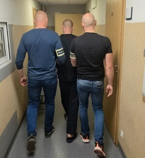 Policjanci prowadzą zatrzymanego mężczyznę