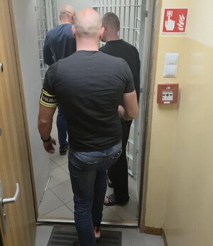 Policjanci prowadzą zatrzymanego mężczyznę