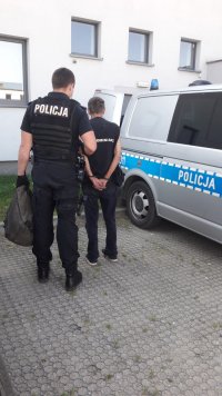Funkcjonariusz prowadzi sprawcę włamań.