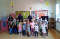 Policjanci stoją z przedszkolakami i opiekunami.