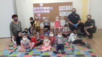 Policjanci siedzą z dziećmi na dywanie.