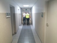 Policjant prowadzi zatrzymanego mężczyznę.