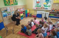 Policjantka siedzi przed dziećmi i rozmawia o odblaskach.