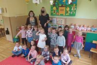 Policjantka siedzi przed dziećmi i rozmawia o odblaskach.