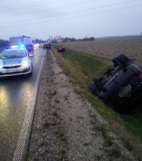 Samochody leżą w przydrożnym rowie, w pobliżu na drodze stoi radiowóz policyjny i wóz strażacki