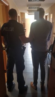 umundurowany policjant prowadzi zatrzymanego mężczyznę