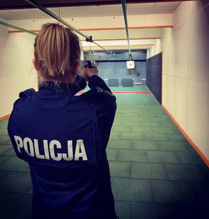 Policjantka odwrócona tyłem celuje do tarczy z broni.