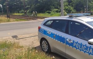 Radiowóz policyjny stoi przy torach kolejowych.